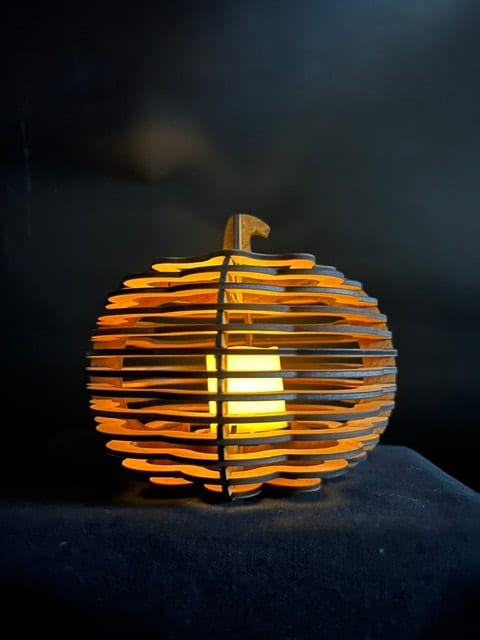 Glowing lasercut wood pumpkin lantern with warm amber light